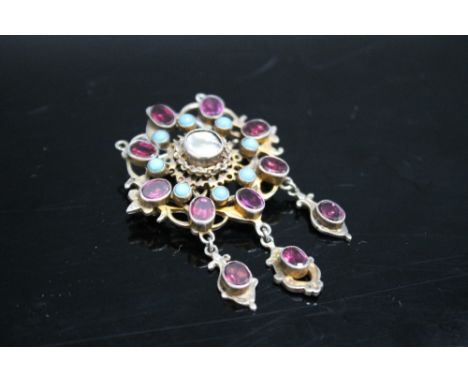 AN EARLY 20TH CENTURY BROOCH, white and gilt metal openwork frame set with oval polished amethyst type gems, turquoise stones
