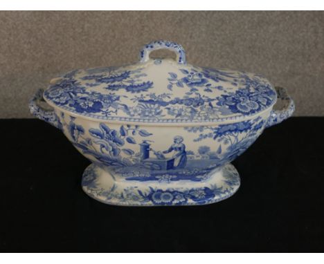 A 19th century blue and white Spode twin handled lidded tureen, decorated with figures in a garden within in floral spray bor