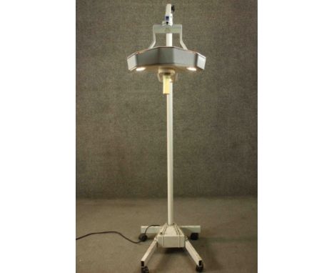 Luxo, a late 20th century dentist's light, with a tri-form top set with three bulbs, on an adjustable arm, attached to a cyli