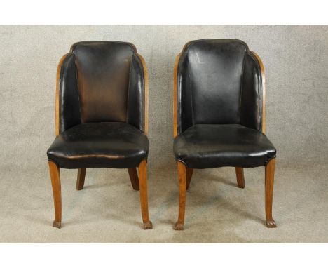 A pair of walnut and black leather Art Deco style chairs raised on tapering supports terminating in pad feet. 