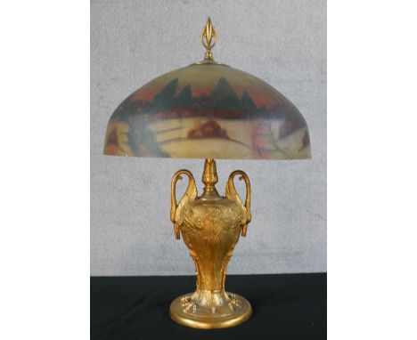 A 20th century table lamp with reverse glass painted light shade, standing on a twin swan/crane head gilt metal base, raised 