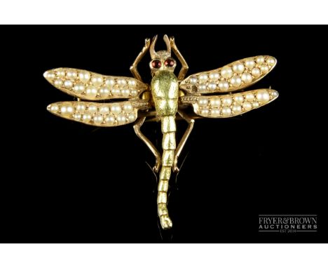 An Edwardian two coloured yellow metal and seed pearl dragon fly clip, ruby cabochon set eyes, the hinged wings with two pron