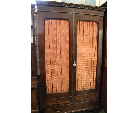 A Georgian gentleman's mahogany wardrobe, the two wire doors lined with red silk above a single drawer, carved pediment, rais