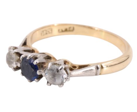 A sapphire and spinel three stone finger ring, having a 4 mm blue sapphire between two white brilliants, on an open gallery b