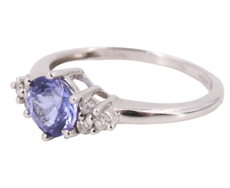 A contemporary tanzanite and diamond finger ring, having a central brilliant of 1.9 carats between adorsed triplets of 1.5 mm