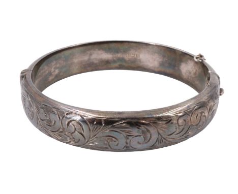 A 1960s silver bangle, decorated with engraved foliate scrolls, internal 54 x 57 mm, 26 g
