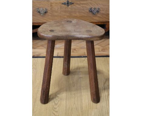 An oak three legged milking stool by Derek 'Lizardman' Slater of Crayke, North Yorkshire, 42 cm high[Derek Slater was apprent