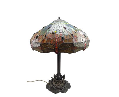 A contemporary Tiffany style patinated metal table lamp, having a cast lily pad base, a compound column, and a leaded glass s