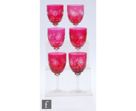 A set of six ruby cased and flash cut wine glasses, the bowls flash cut through to clear crystal with a band of stylised flow