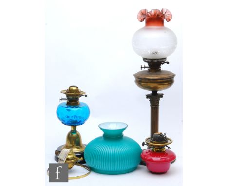 A 20th Century brass oil lamp and shade, another with blue reservoir and one other with chimneys, frames and shades. 