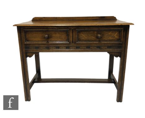 A small Jacobean revival light oak two drawer side table with ledge back, on square moulded legs united by a rail stretcher, 