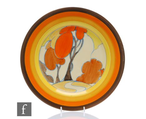 A large Clarice Cliff circular plate circa 1932, hand painted in the Orange Autumn pattern with a stylised tree and cottage l