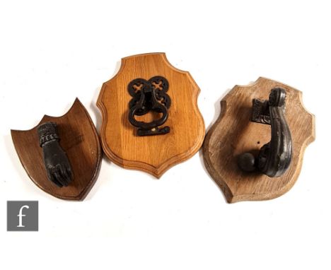Two late Victorian cast iron door knockers, the first with a quatrefoil pierced back and trefoil shaped knocker, on later woo