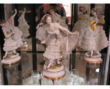 A set of four German porcelain figures of dancers, with exuberant lace dresses, 30cm high 
