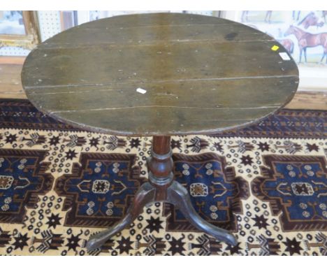 A George III oak tripod table, the oval planked top on a turned stem and cabriole legs, 74cm wide