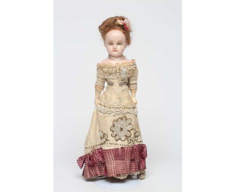 A Victorian wax shoulder head doll with blue glass paperweight fixed eyes, closed mouth, light brown wig, fabric body, compos