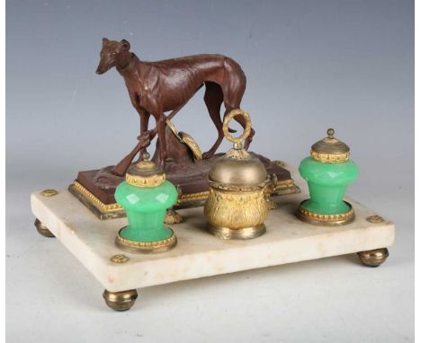 A late Victorian white marble and gilt metal mounted ink stand with a cast spelter hunting dog surmount, the green glass inkw