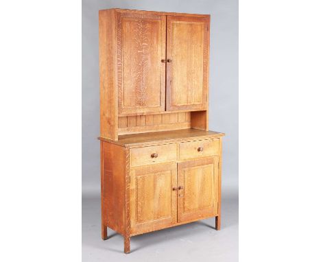 An early 20th century oak side cabinet by Heals, the two panelled doors above an open shelf, two drawers and further doors, o