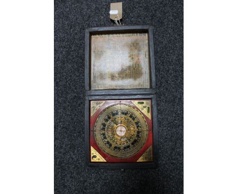 A 20'th Century Chinese compass ornately mounted inside a larger metal dial set within a square panel, in a metal-bound and l