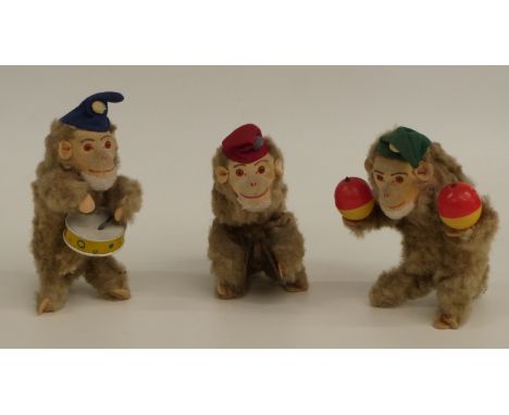 A set of three M Toys of West German clockwork mohair covered tinplate monkeys, all in the form of a band playing a drum, cym