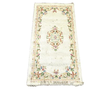 A runner with floral design on cream field, 183 x 97 cm, and another rug in earth tones, (2).&nbsp;