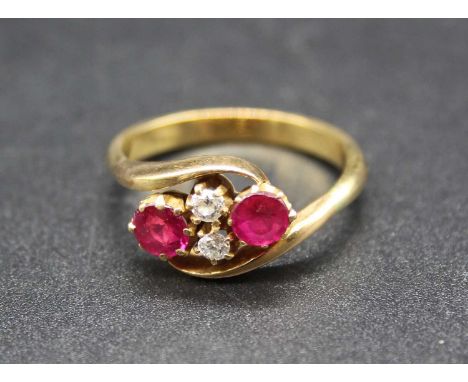 A yellow metal, ruby and diamond crossover ring, arranged as two round cut rubies dispersed by a pair of small old round cut 