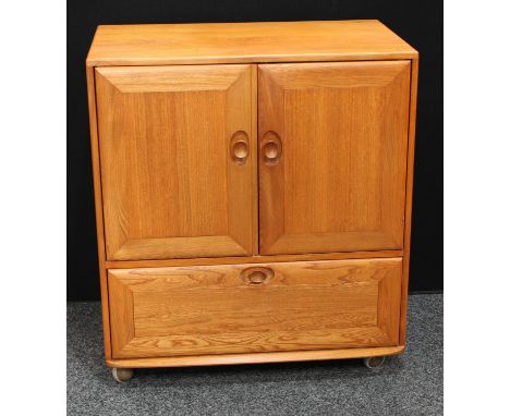 An Ercol elm TV/media cabinet, the two panel doors hinged and retractable above a fall front enclosing a fitted sliding plate