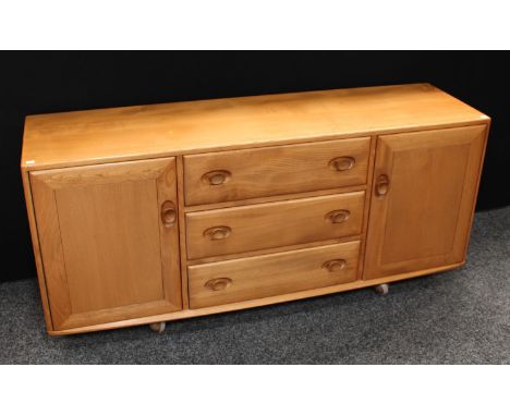 An Ercol elm sideboard, flush rectangular top above three central short drawers, flanked by a pair of cupboard doors, each en