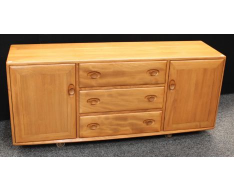 An Ercol elm sideboard, flush rectangular top above three central short drawers, flanked by a pair of cupboard doors, each en