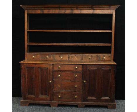 A Farmhouse pine dresser, outswept cornice above open shelves and six small drawers, the projecting base with four central sh