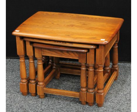 An Ercol elm nest of three occasional tables, the largest 62.5cm wide