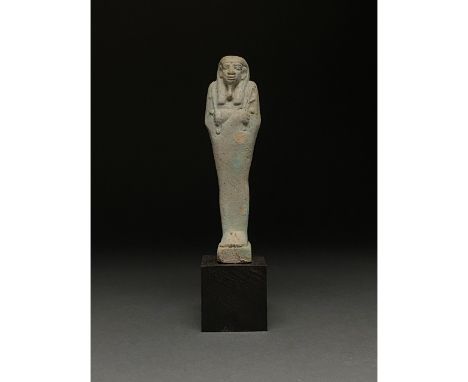 Ca.1070-945 BC Egyptian. A light blue faience ushabti figure wearing a tripartite wig, a false beard and holding two flails. 