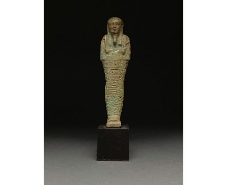 Ca.1070-945 BC Egyptian. A light green faience ushabti figure wearing a tripartite wig, a false beard and holding two hoes. S