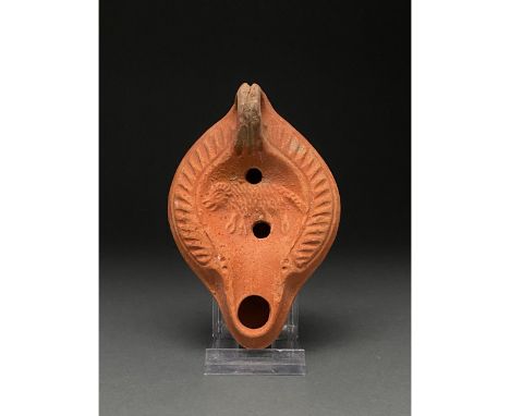 Ca. 1-300 AD. Roman. A beautiful terra sigillata lamp depicting a wolf enclosed by a wreath of incised grooves. The oldest Ro