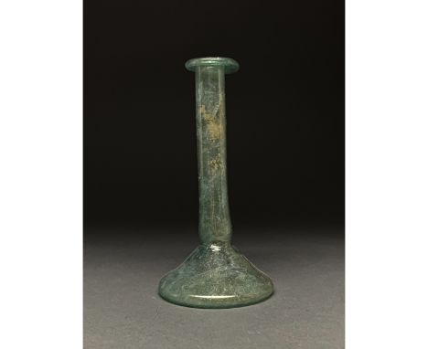 Ca. 1-300 AD Roman. A Roman candlestick unguentarium in a green glass, featuring a short globular body with a concave base, a
