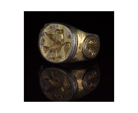 1100-1500 AD. Medieval. Large silver gilt ring with D-shaped hoop, with applied shields containing wing motifs on each should