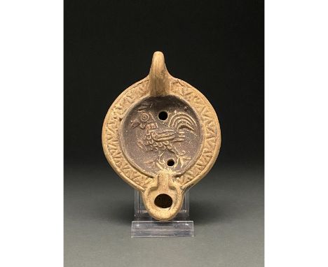 1-300 AD. Roman. A beautiful ceramic lamp depicting a strutting cockerel with intricate stylized geometric feathers surrounde