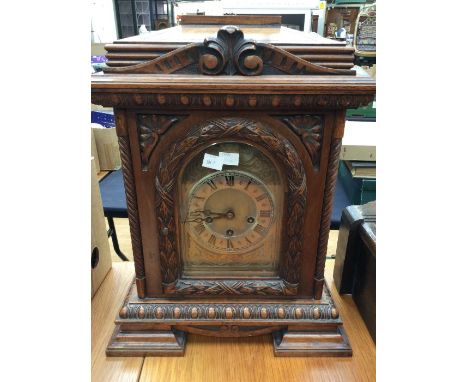 Large late Victorian table clock with Junghans three-train movement, chiming on rods. Contained in oak case carved with leave