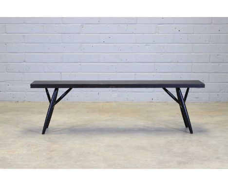 A Finnish 'Pirkka' bench, originally designed in 1955 by Ilmari Tapiovaara, the plank top raised on turned ebonised supports,