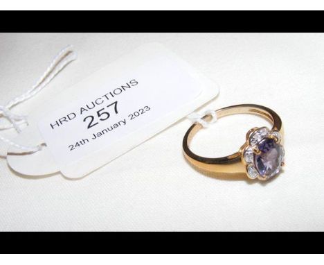 A 9ct dress ring with oval purple stone and diamond mount