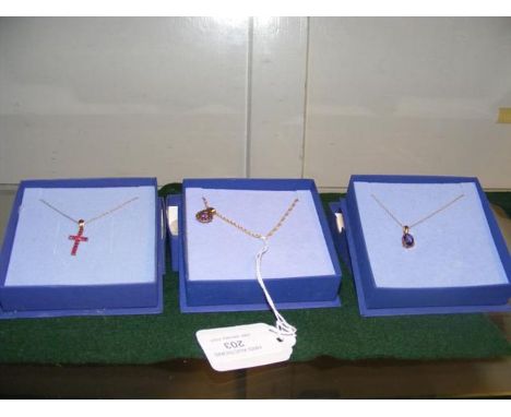 A 9ct gold ruby cross pendant on gold chain together with two others