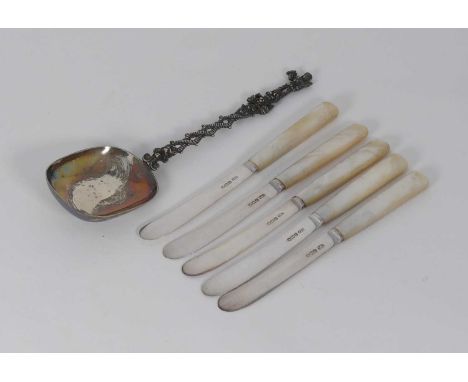 A set of five silver bladed mother-of-pearl handled butter knives, together with a silver serving spoon, having an ornate han