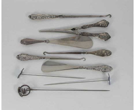 A collection of Victorian silver handled implements to include shoe horn, glove stretchers, button hook etc, and three hat pi