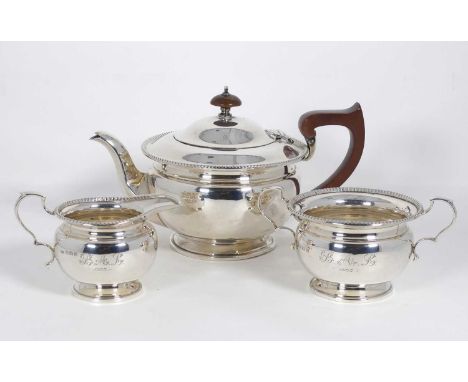 A George V silver three-piece tea service, having a beaded rim and wooden handle, Birmingham 1933, gross weight 21ozt 