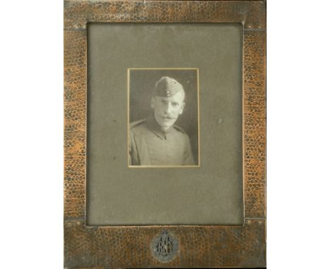 A glazed copper framed portrait photograph of an unidentified member of the Royal Flying Corps in uniform with Royal Flying C