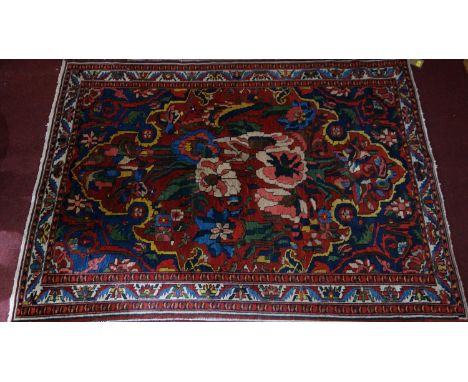 A Persian carpet with floral motifs on a red ground, contained by floral borders, 207 x 150cm 