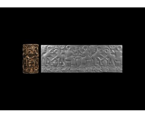 3rd millennium BC. A large serpentine cylinder seal with deeply carved frieze of two opposed seated figures with an amphora b