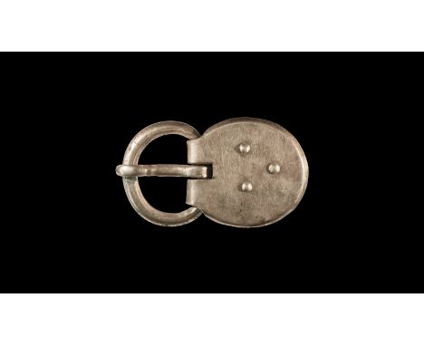 6th century AD. A large silver buckle comprising a round-section loop, curved tongue with tip resting on the loop, domed disc
