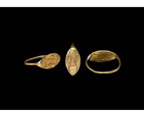 1st millennium BC. A gold finger ring comprising a slender flat-section hoop, scaphoid plaque with incised image of two addor