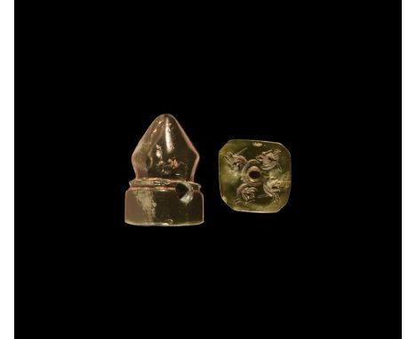 3rd-7th century AD. A dark brown agate stamp seal with pointed finial top; square base engraved with four got heads forming a